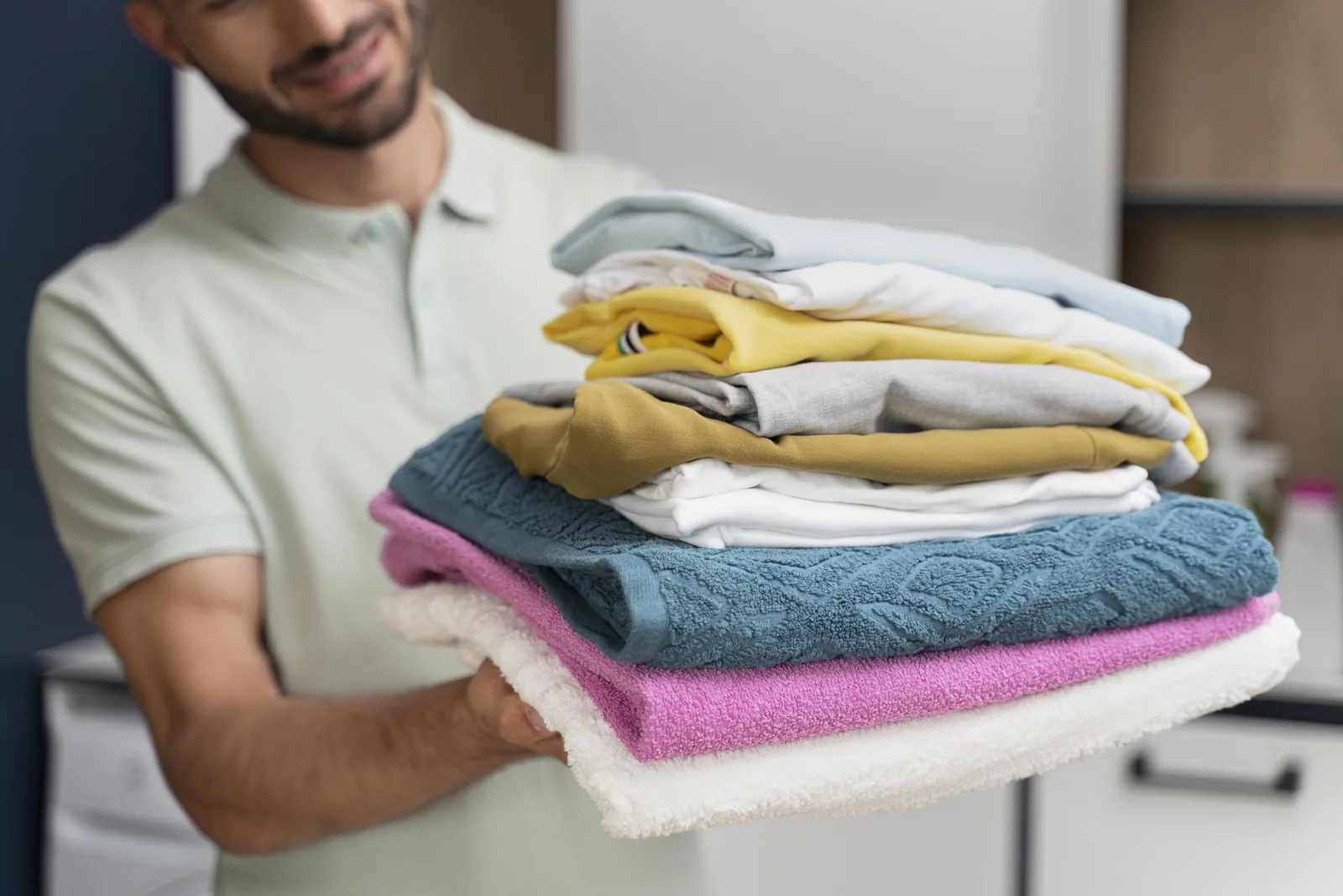 A satisfied customer holding a pile of clean Wasro-washed clothes